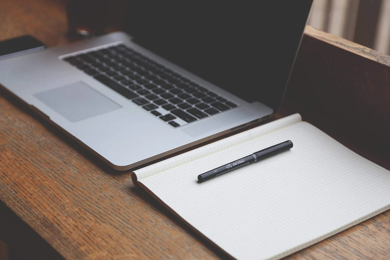 Laptop and notebook on a wooden desk